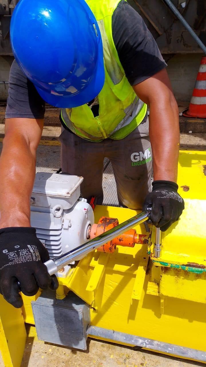 Aperto de parafusaria de motor elétrico industrial com torquímetro, fundo amarelo