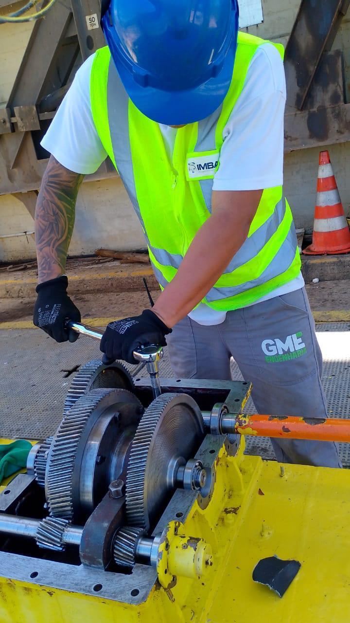 Técnico de capacete azul montando engrenagens industriais de grande porte com torquímetro