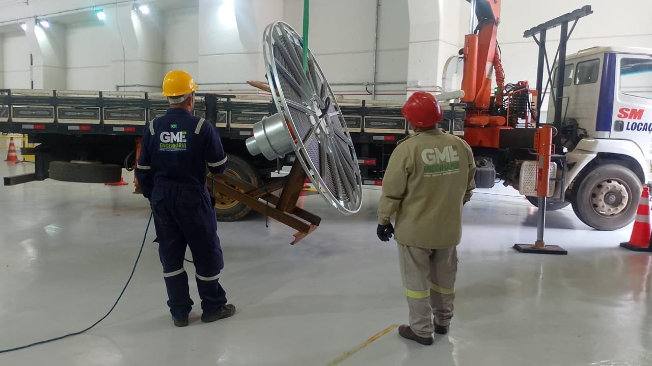 Dois técnicos observando manobra de carga com caminhão munck
