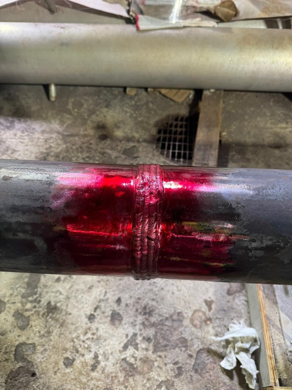 Detalhe de cordão de solda circunferencial em tubo metálico com pintura de identificação vermelha
